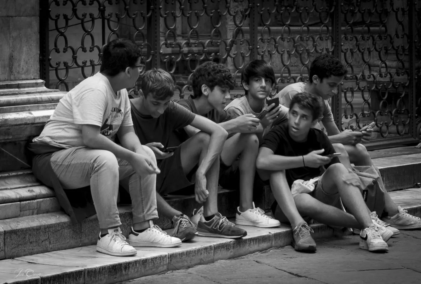 Tieners op stenen trappen, de meesten op hun smartphone